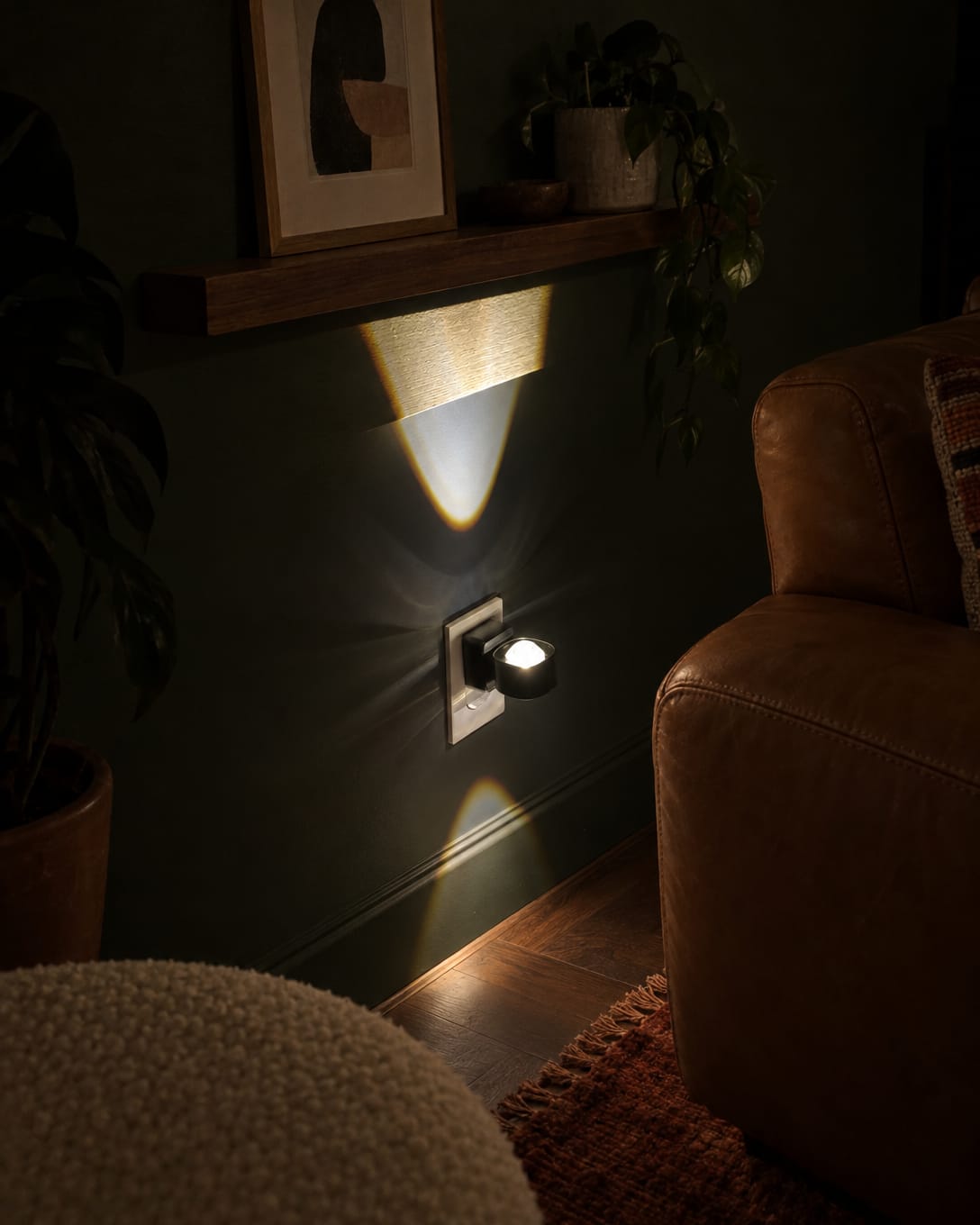 Aoraglow glowing warm up and down the wall behind a sofa in a living room at night, true to its size beside the outlet, the