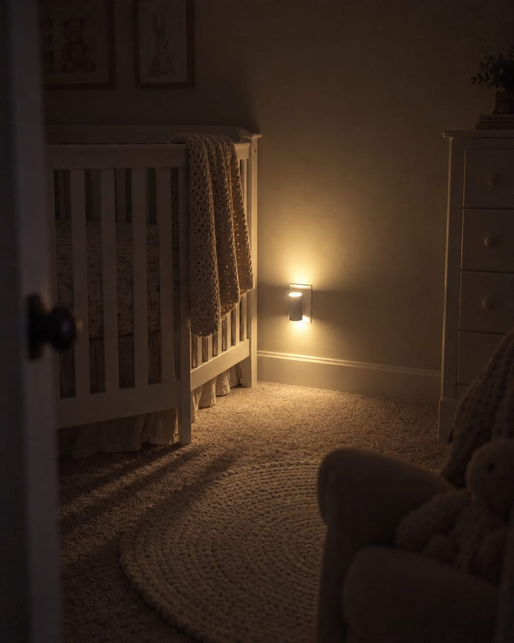 Aoralight - Home Glow Kit glowing soft amber low on a nursery wall at night, small beside the outlet plate, the room calm