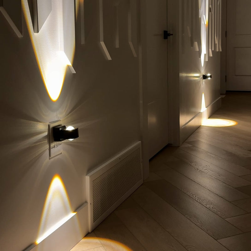 Aoraglow glowing warm up and down a wall at night beside its outlet plate, the room dim and calm, cut square for the head of